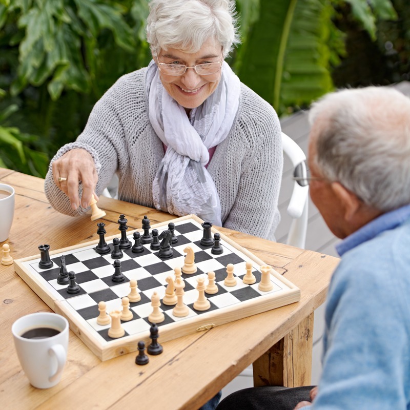 Senior woman and man playing chess in the outdoor courtyard